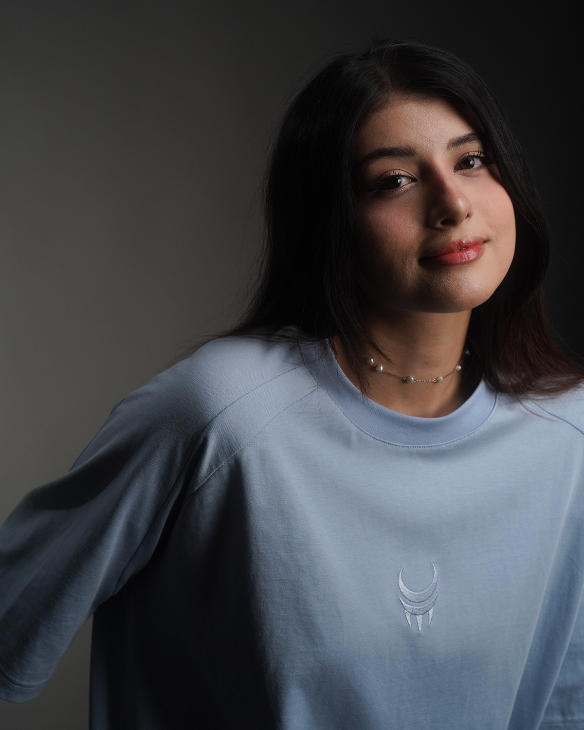 Hellblaues T-Shirt mit weißem „MoonClaw“-Krallensymbol mittig auf der Brust, getragen von einer Frau.