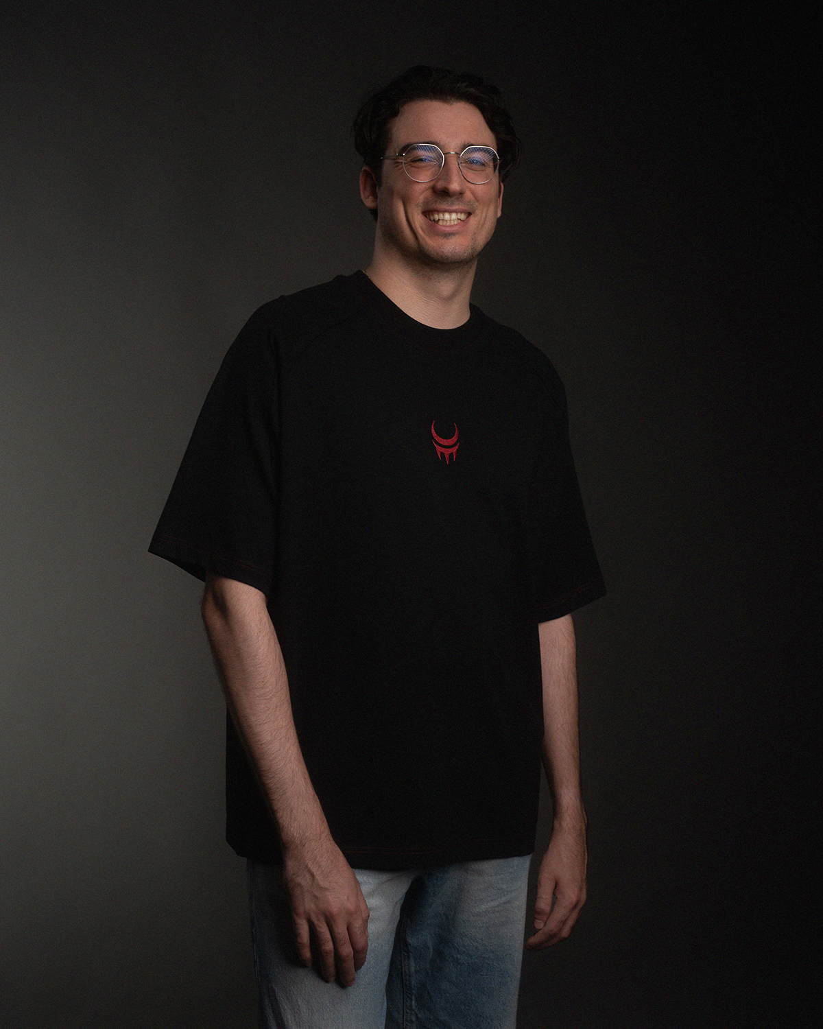 Person trägt ein schwarzes T-Shirt mit rotem Mondkrallen-Logo mittig auf der Brust.