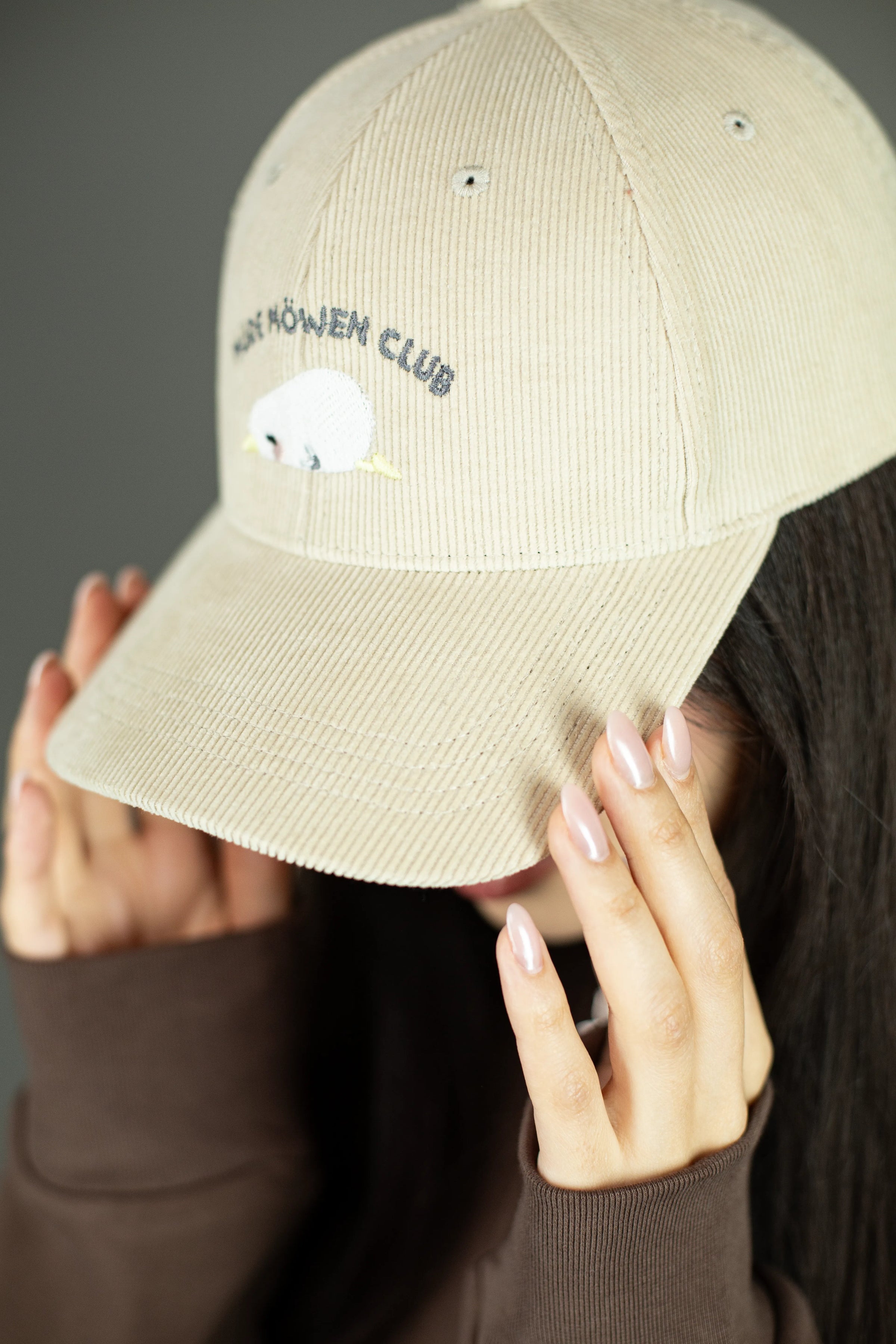 Detailaufnahme der beigefarbenen Cord-Cap mit sichtbarer Stickerei „MÜDE MÖWEN CLUB“ und schlafender Möwe mit gelbem Schnabel. Der Fokus liegt auf der feinen Cordstruktur und der gestickten Oberfläche.