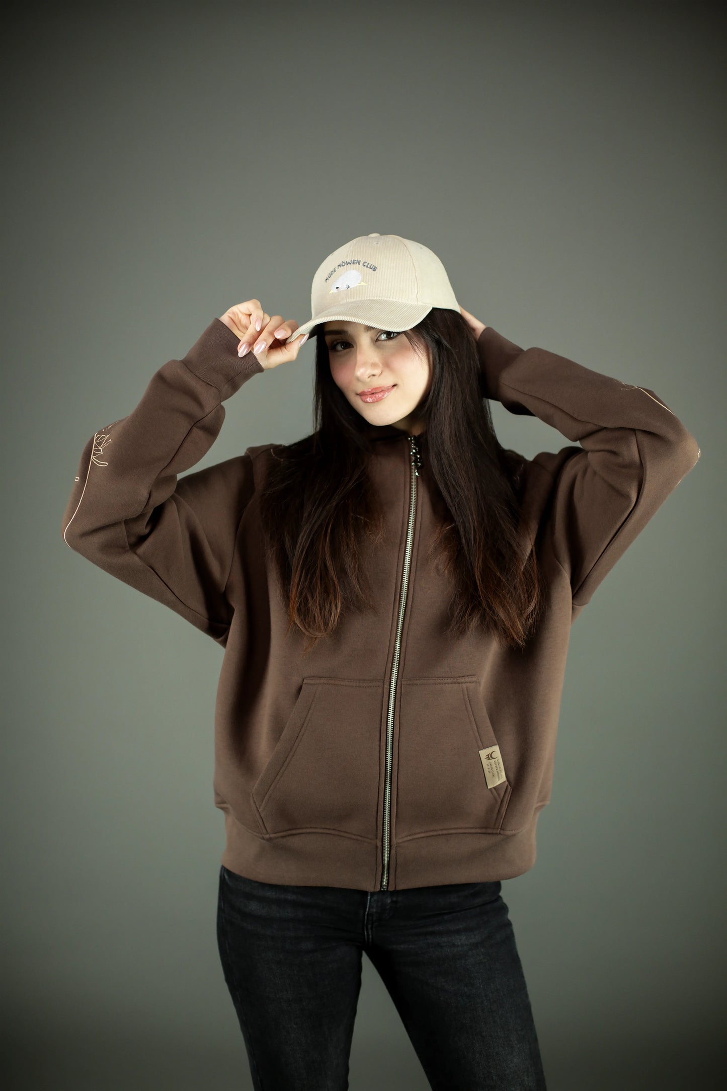 Beigefarbene Cord-Cap mit gesticktem Schriftzug „MÜDE MÖWEN CLUB“ und kleiner Möwenillustration in der Mitte. Der Schirm ist leicht gebogen, die Cap wird locker mit beiden Händen am Rand gehalten.