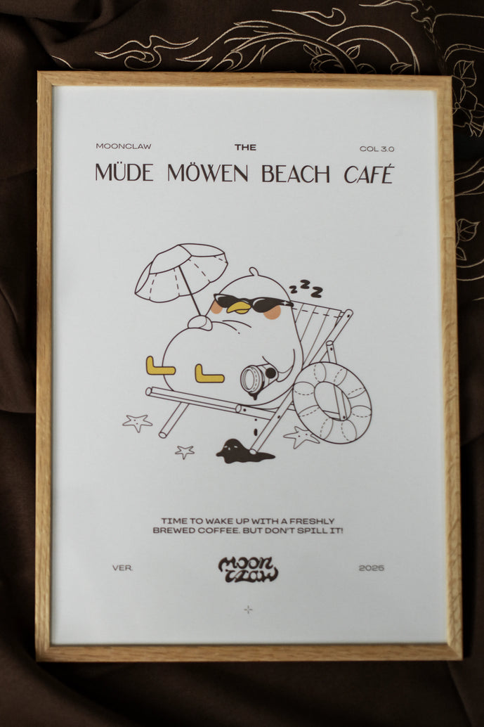 Gerahmtes Poster mit der Aufschrift „MÜDE MÖWEN BEACH CAFÉ“ und Illustration einer entspannt liegenden Möwe mit Sonnenbrille im Liegestuhl unter Sonnenschirm. Unter dem Motiv steht der Satz „Time to wake up with a freshly brewed coffee. But don’t spill it!“. Der Druck ist in einem hellen Holzrahmen gefasst und liegt auf braunem Stoff mit feinen Stickmustern.